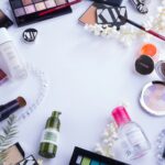 Flat lay of beauty essentials including skincare bottles, brushes, and makeup tools for glowing skin