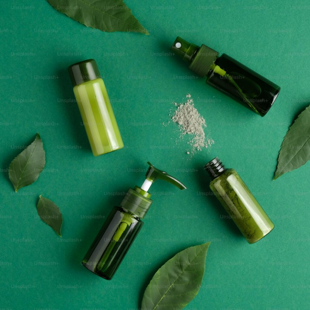 Flat lay of green skincare bottles with natural botanical ingredients on green background