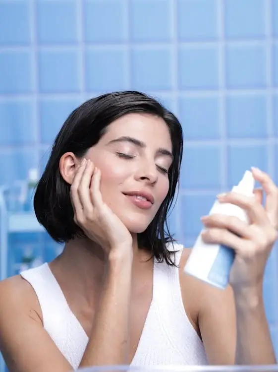 Woman applying facial mist as part of her skincare essentials routine